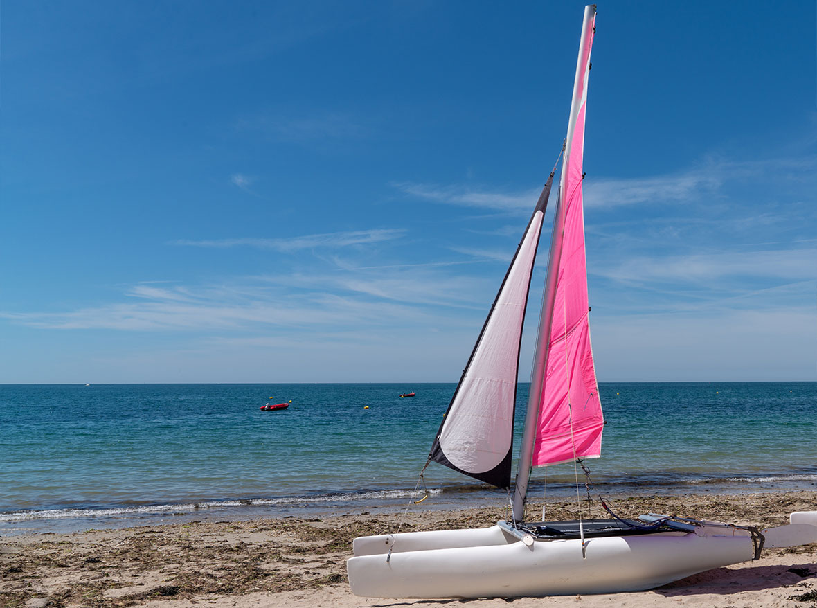 Pink sailed boat resting on the sand on the coast of Vendée beach